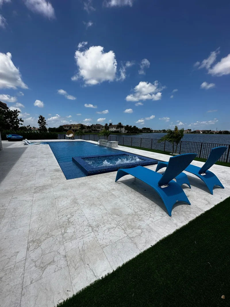 Blue loungers on the deck of a pool and spa by a lake