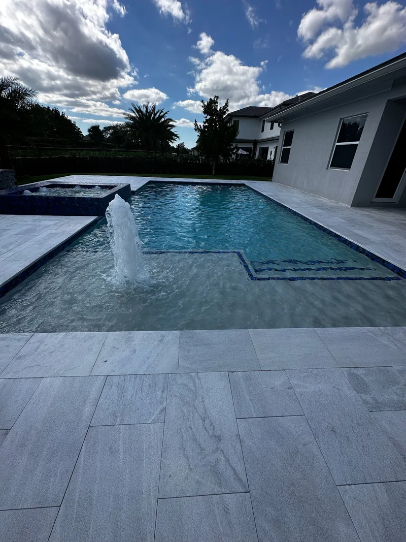 Bubbler in a pool next to a white home
