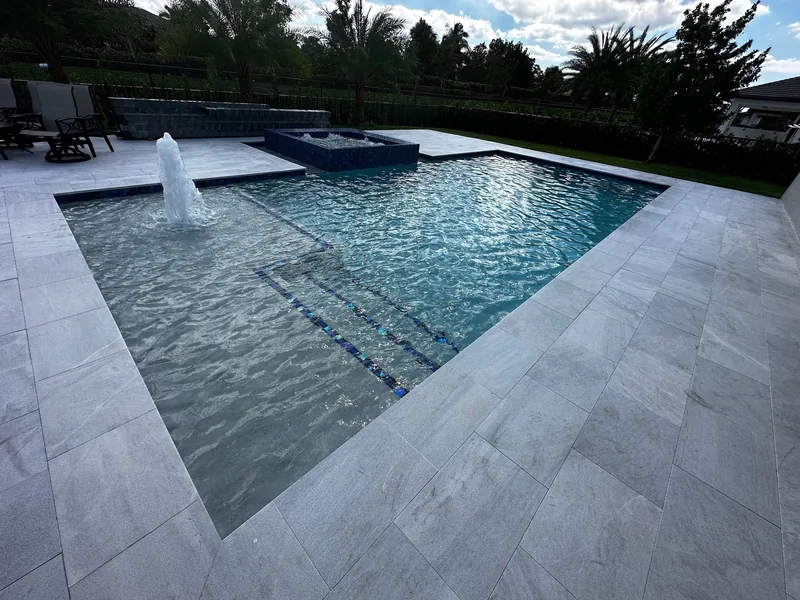 Deck jets arcing over a pool ledge in evening light