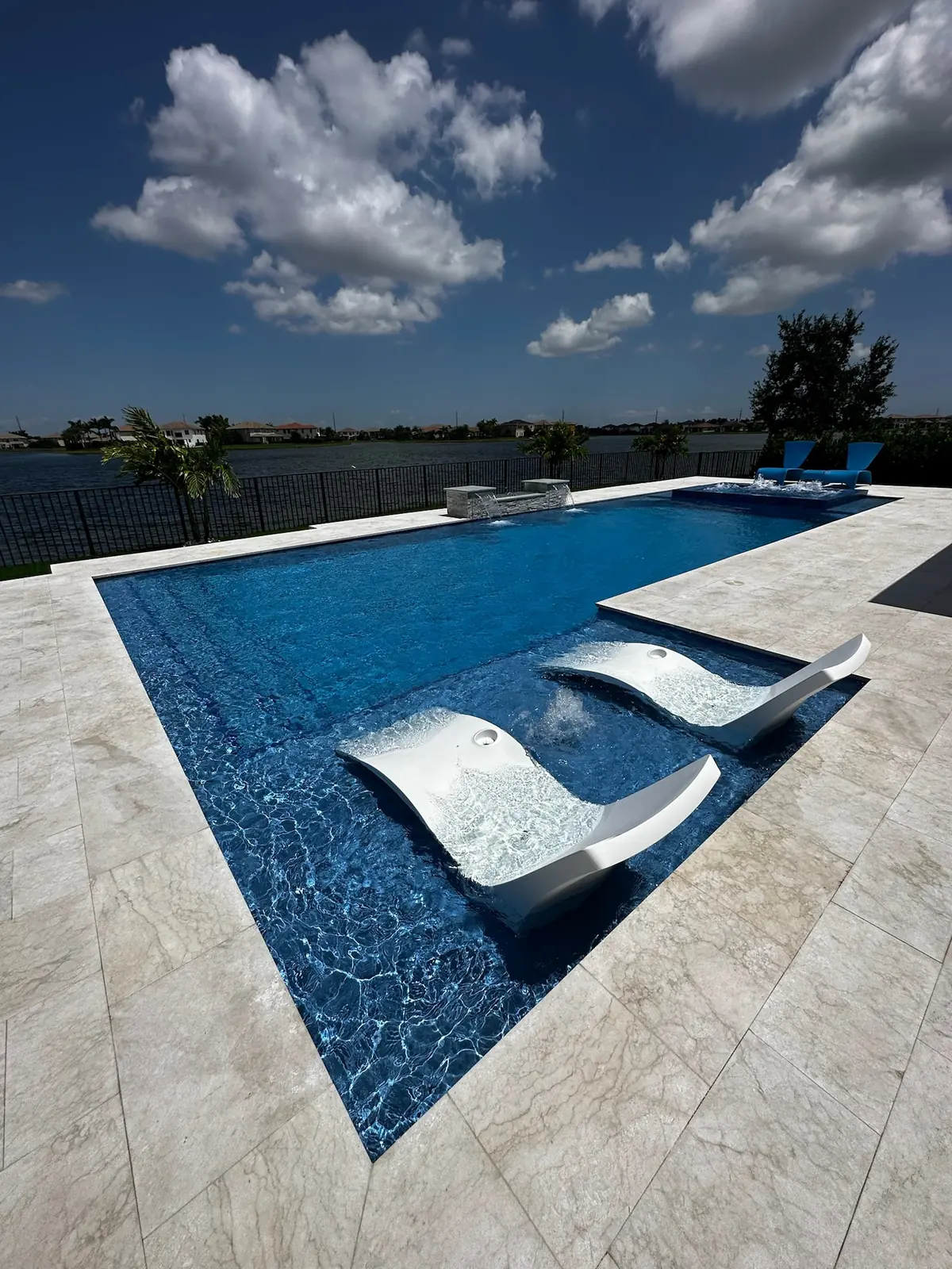 In-pool loungers on a sun shelf lined with dark blue tile