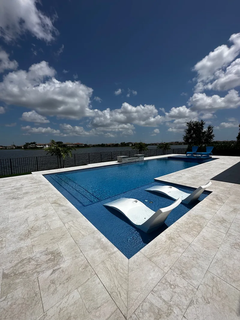 In-pool loungers on a sun shelf of a long pool facing a lake