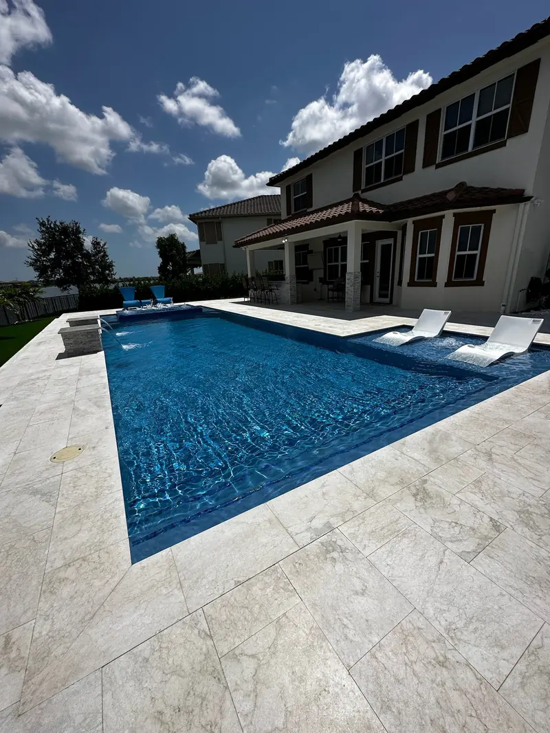 In-pool loungers in a blue pool in front of a two-story home