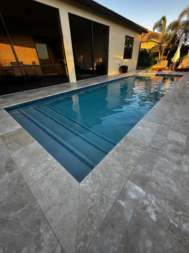 Pool beside a lit covered lanai at dusk