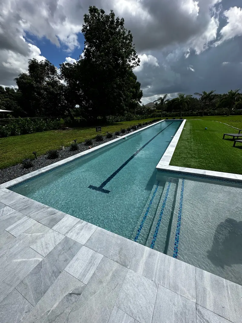 Lap pool with a lane line, white coping and turf