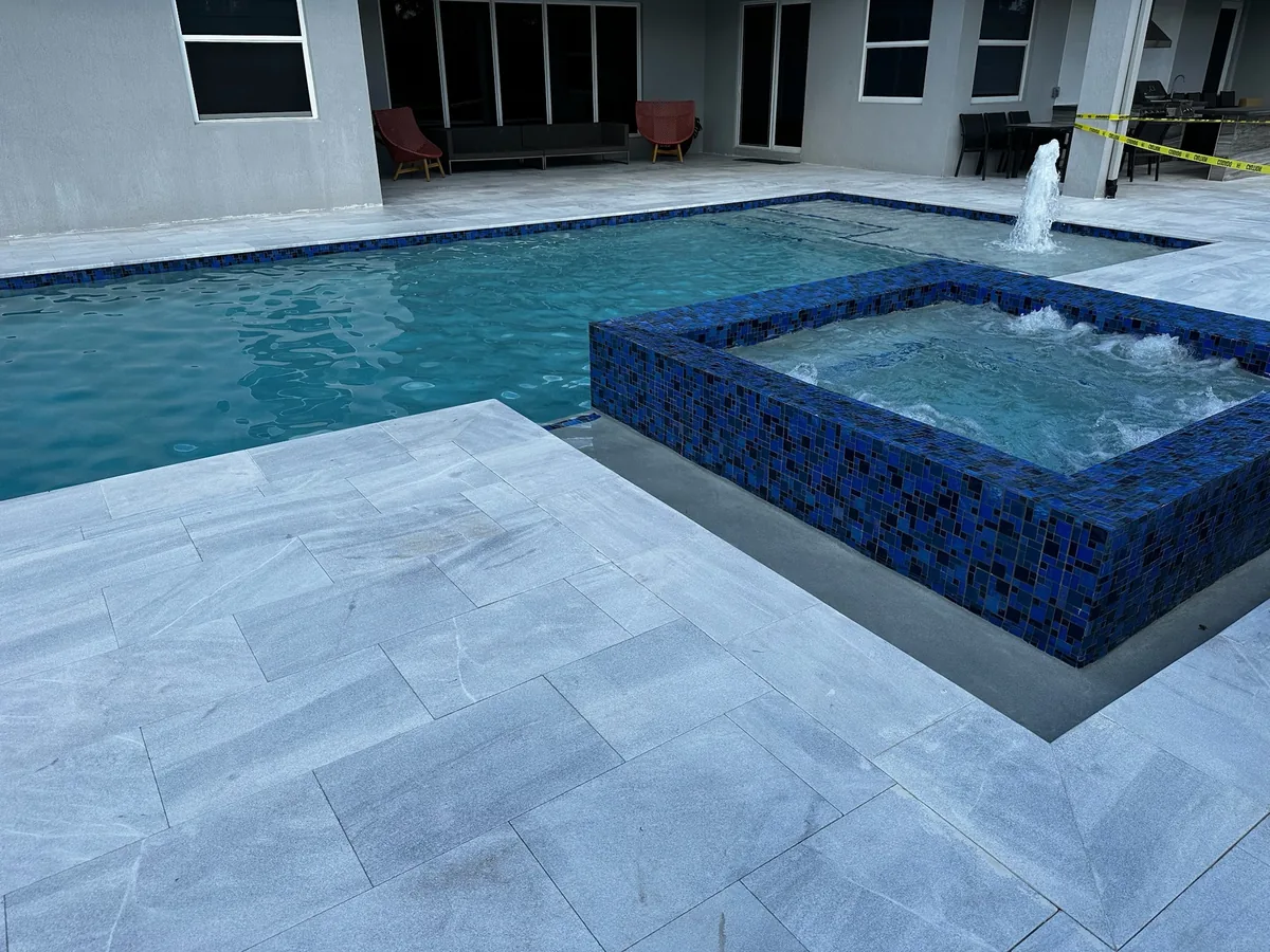 Raised mosaic spa spilling into the pool next to the patio