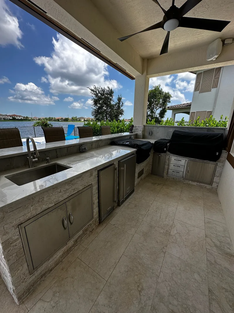 Outdoor kitchen under a covered lanai with a lake view