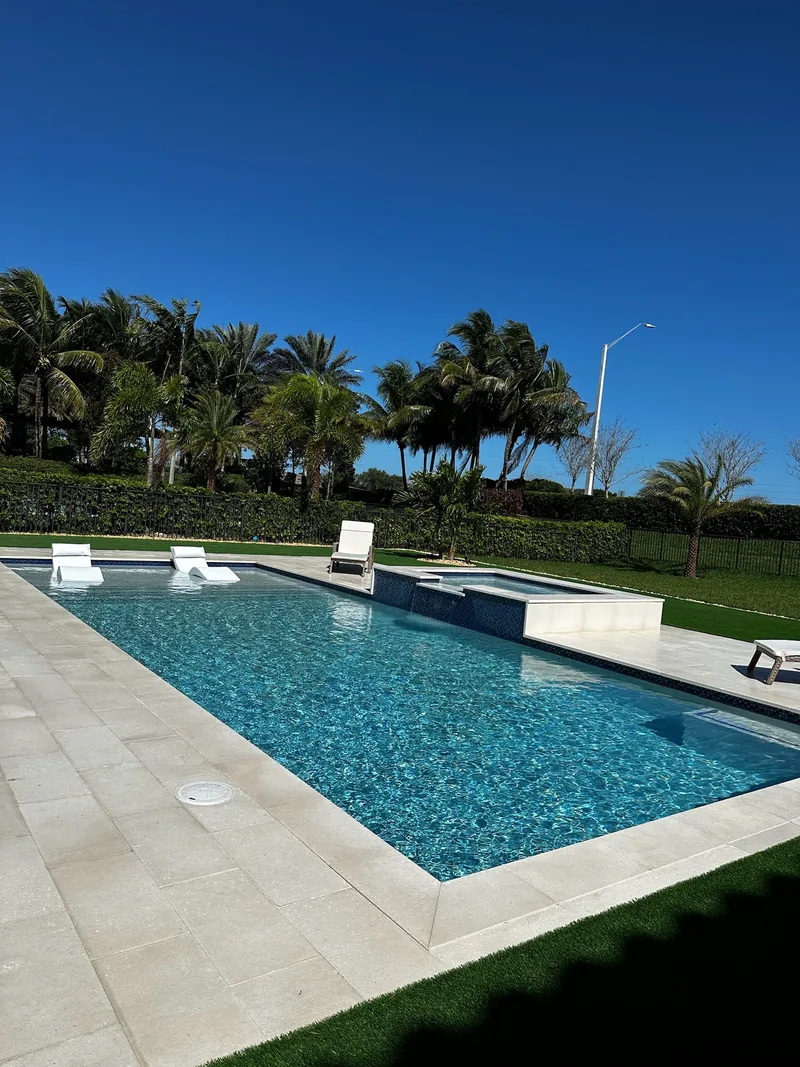 Pool with white loungers, turf and palms