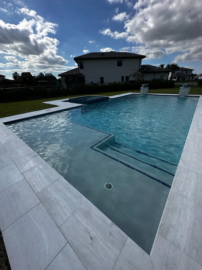 Pool with wide entry steps and a ledge, two-story home behind