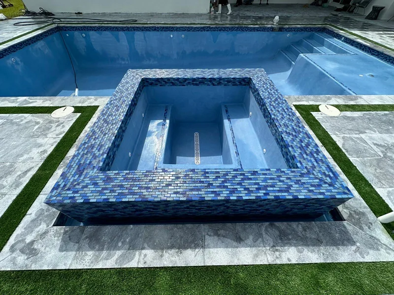 Raised mosaic-tile spa with a turf border around the deck