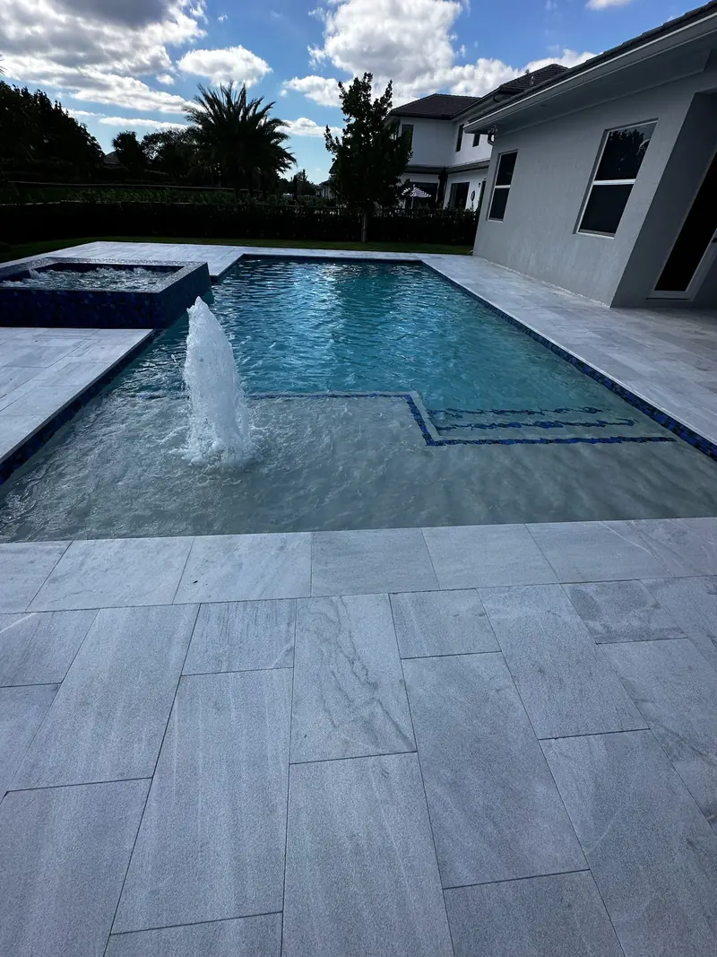 Raised spa and a bubbler on the steps of a white-deck pool