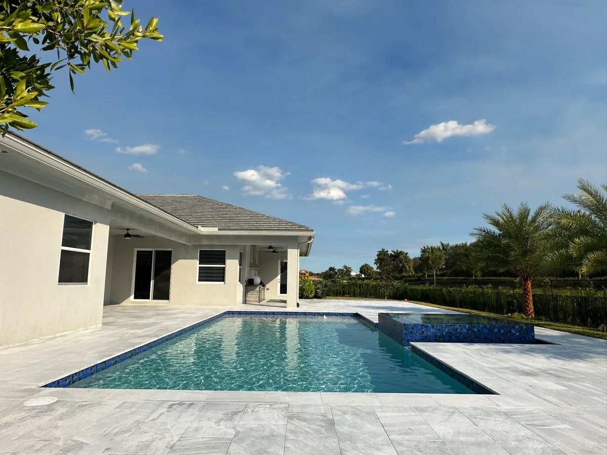 Single-story white home with a rectangular pool and a raised blue mosaic spa