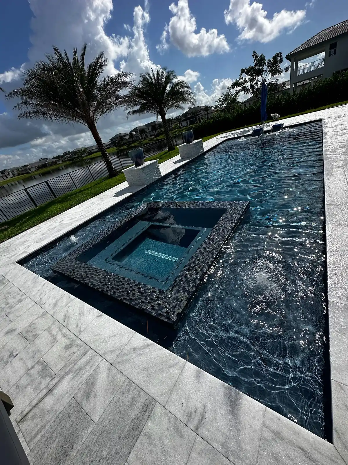 Raised spa set inside a long pool on a lake lot with palms