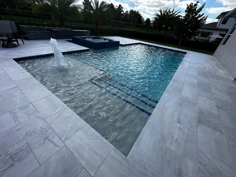 Sun shelf with a bubbler and blue tile lines, white travertine deck