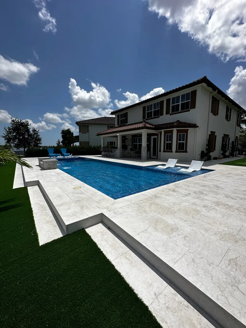 Two-story home with a long pool, white deck and turf