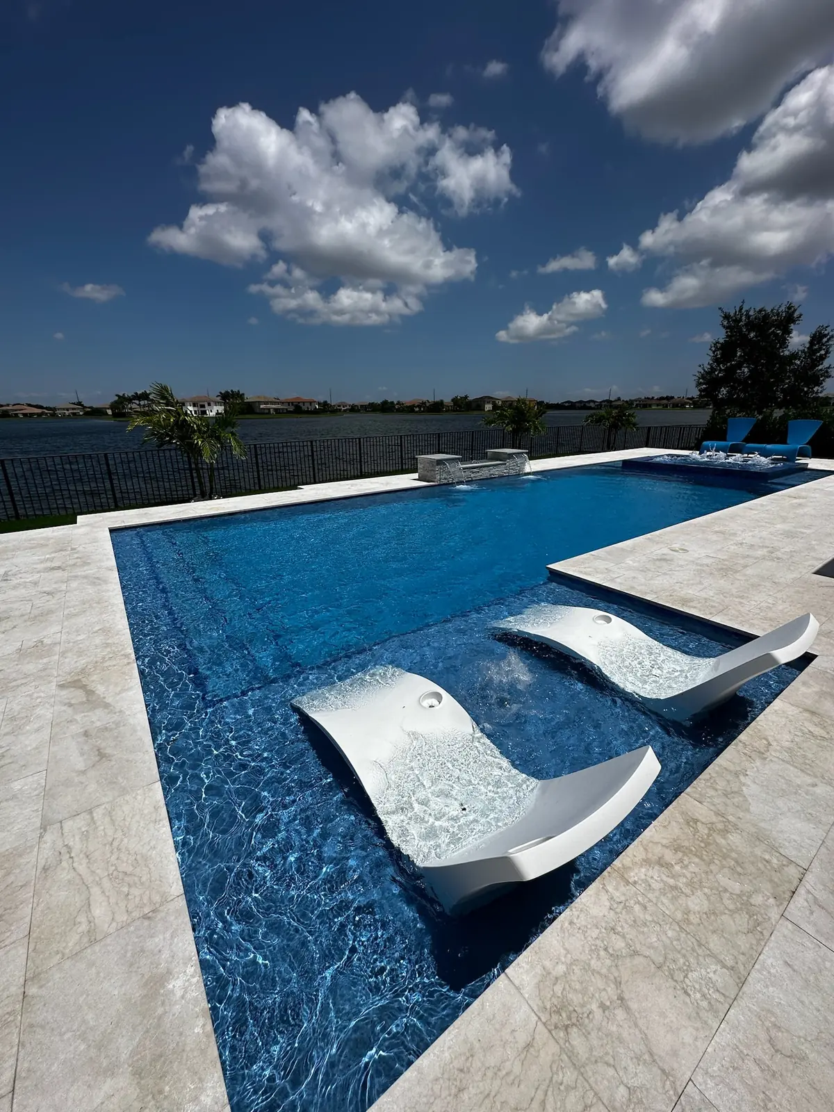 Close view of white in-pool loungers on a sun shelf lined with blue tile