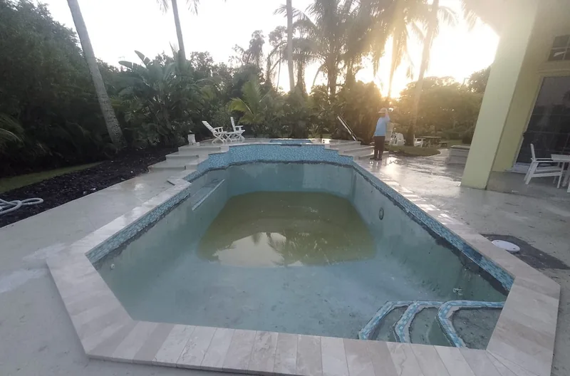Pool outlined with newly laid stone coping on a paver deck at sunset