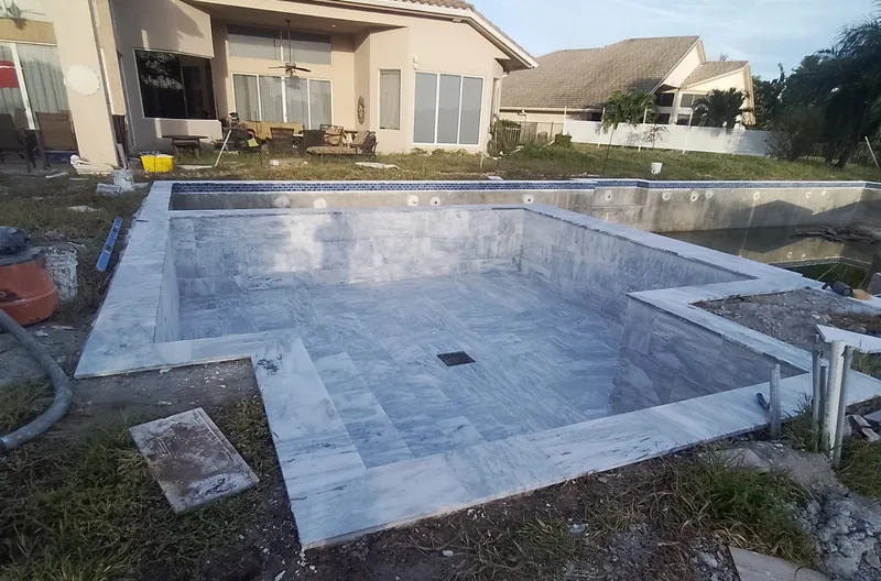 Large pool shell with a raised edge and stone tile on the walls on a construction site