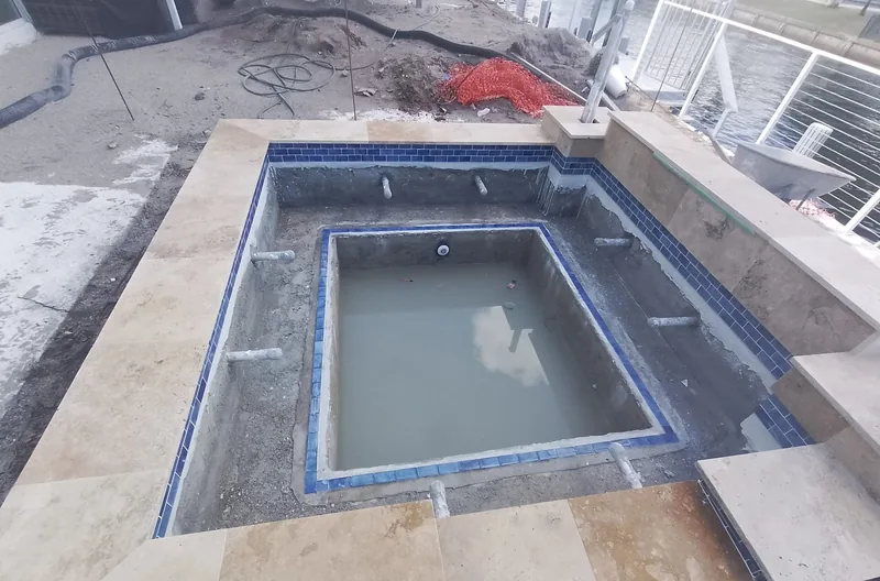 Rectangular raised spa under construction with stone coping set around it