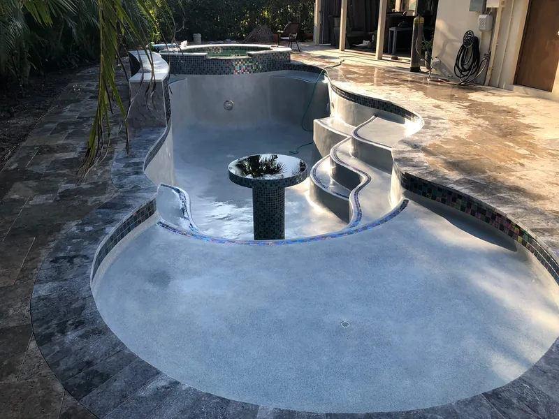 Freeform pool with stepped seating, a raised bowl feature and stone coping