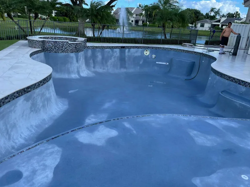 Freeform pool with an attached spa, tile border and lake in the background