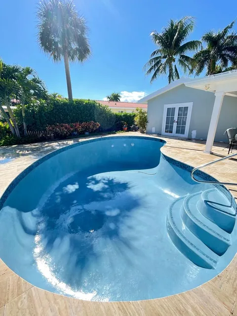Freeform pool with a stepped entry and travertine coping, filled with water