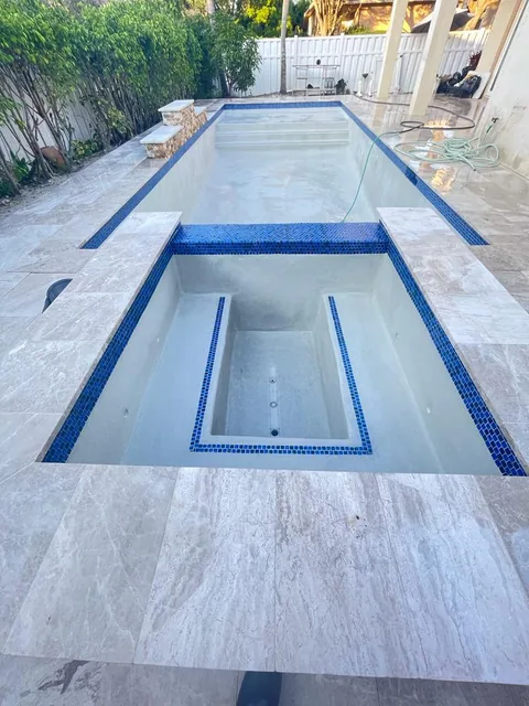 Long narrow pool with a tiled spa at one end and light stone decking