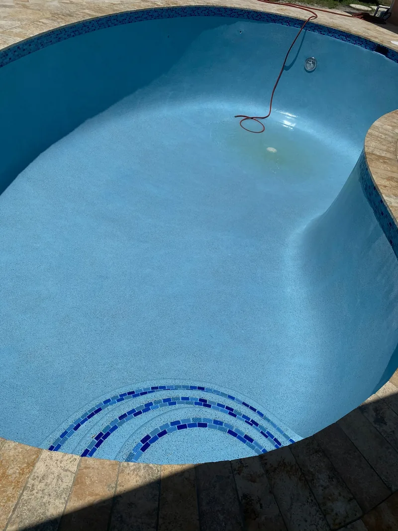 Curved pool wall with a blue mosaic inlay at the waterline