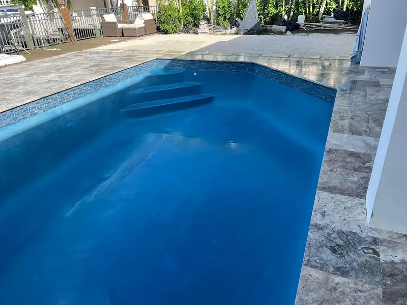 Rectangular blue pool with a full-width step and travertine coping
