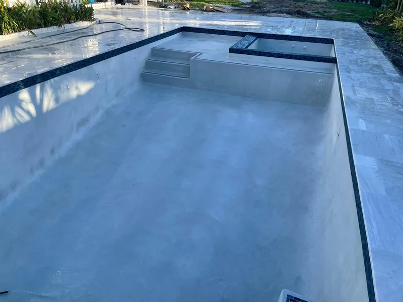 Large pool with a raised spa and a dark tile band along the waterline