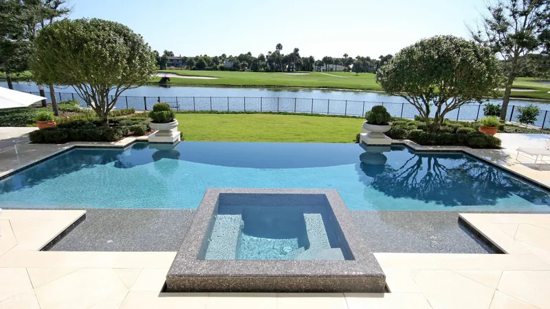Raised spa set inside a freeform pool with a golf-course view behind it