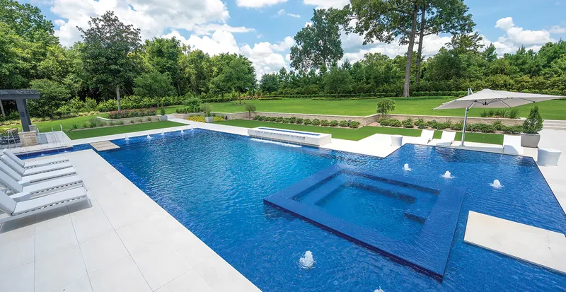 Sun shelf with bubblers and in-pool loungers in a dark-blue tile pool