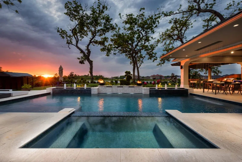 Pool with sun shelves beside a covered lanai at sunset