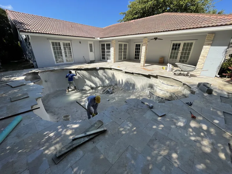 Crew laying the new travertine deck around the drained pool
