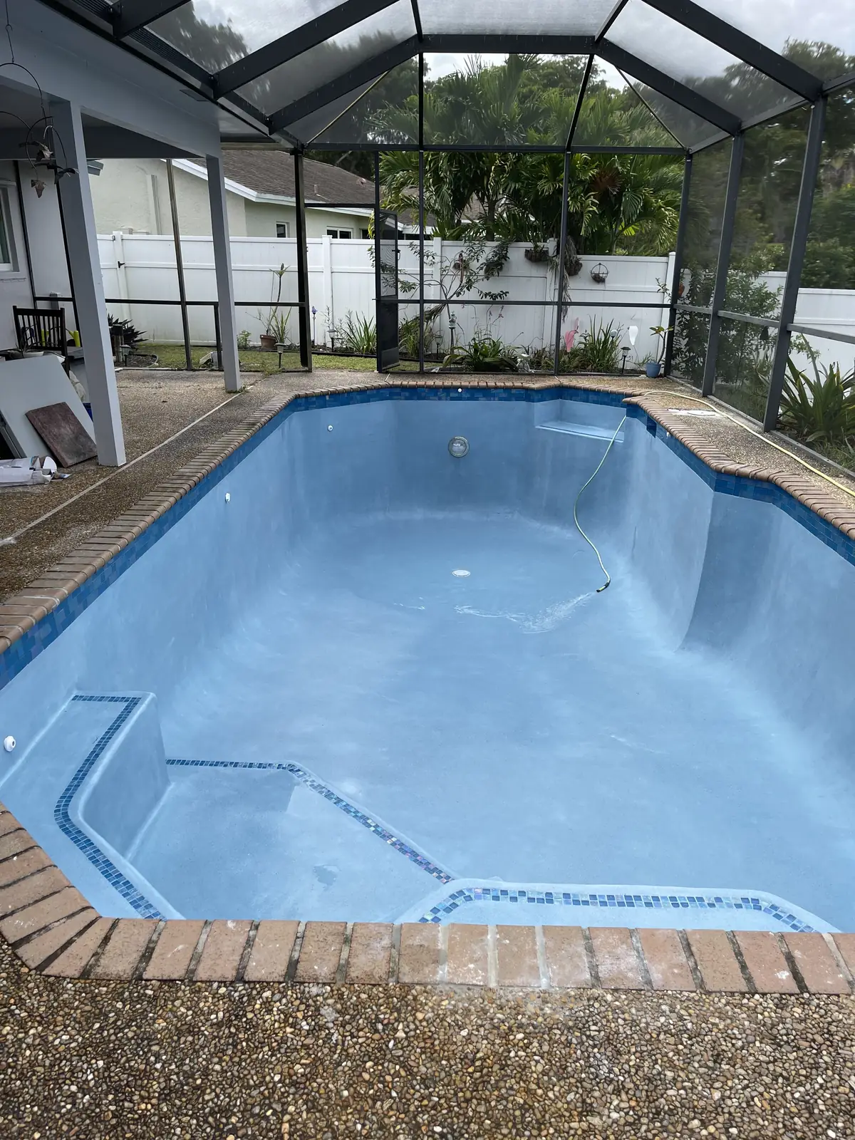 Screened pool with a new blue finish and brick coping, ready to fill
