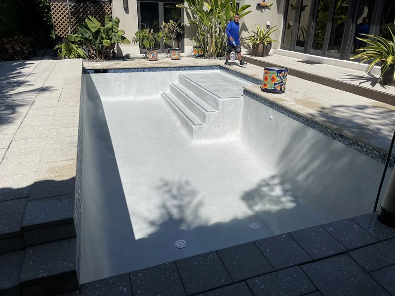 Rectangular pool with a fresh white plaster finish and wide entry steps, before the fill