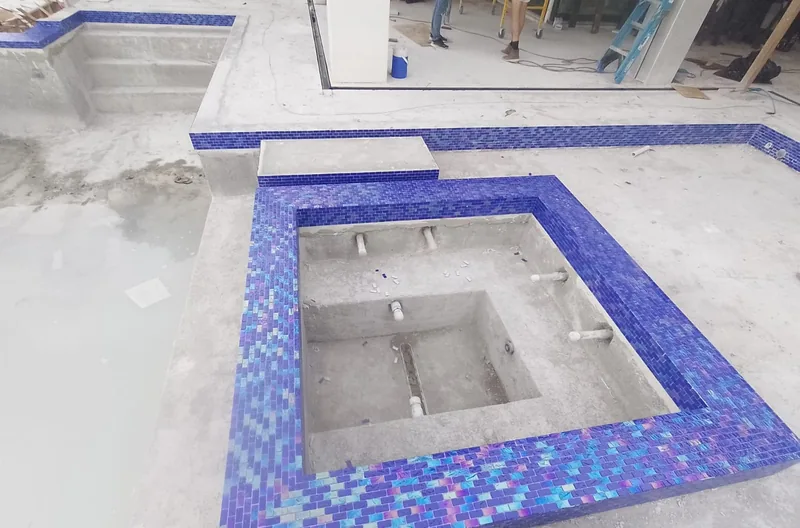 Spa walls faced with iridescent blue glass tile with a pool behind